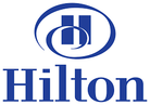 Hilton logo featuring a stylized letter H enclosed within two overlapping oval shapes above the word Hilton in bold, blue capitalized letters on a plain white background. Hilton logo featuring a stylized letter H enclosed within two overlapping oval shapes above the word Hilton in bold, blue capitalized letters on a plain white background.