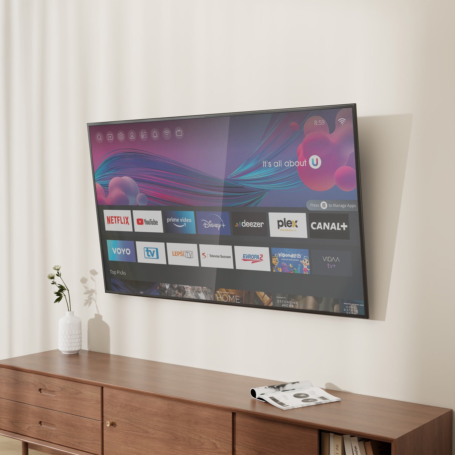 Flat-screen TV mounted on a wall using the Mount-It! Low Profile Tilt TV Wall Mount, featuring a slim 1-inch profile and tool-free tilt adjustment, positioned above a wooden dresser in a modern living space with a small plant and magazine nearby.