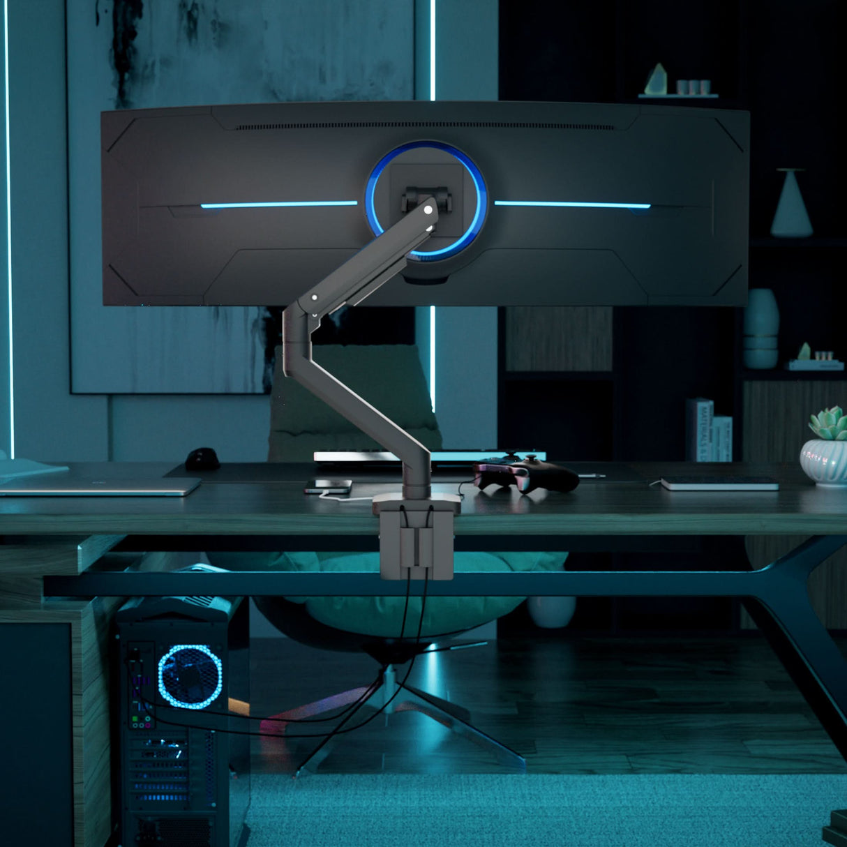 A Mount-It! Heavy-Duty Monitor Mount with Gas Spring Arm holds a wide curved monitor above a modern desk in a dimly lit gaming setup, featuring blue accent lighting, tidy cables, shelves in the background, and a gaming PC on the floor.