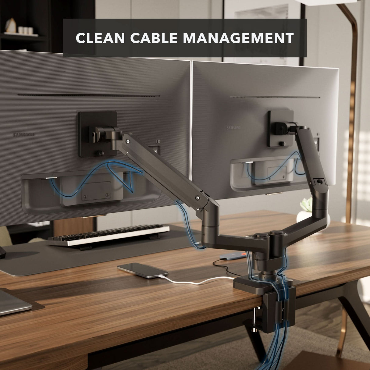 Two monitors mounted on the Mount-It! Heavy-Duty Dual Monitor Mount with Gas Spring Arms, featuring organized cables and set on an ergonomic desk with a keyboard, mouse, and notepad. Text overlay: “CLEAN CABLE MANAGEMENT.”.