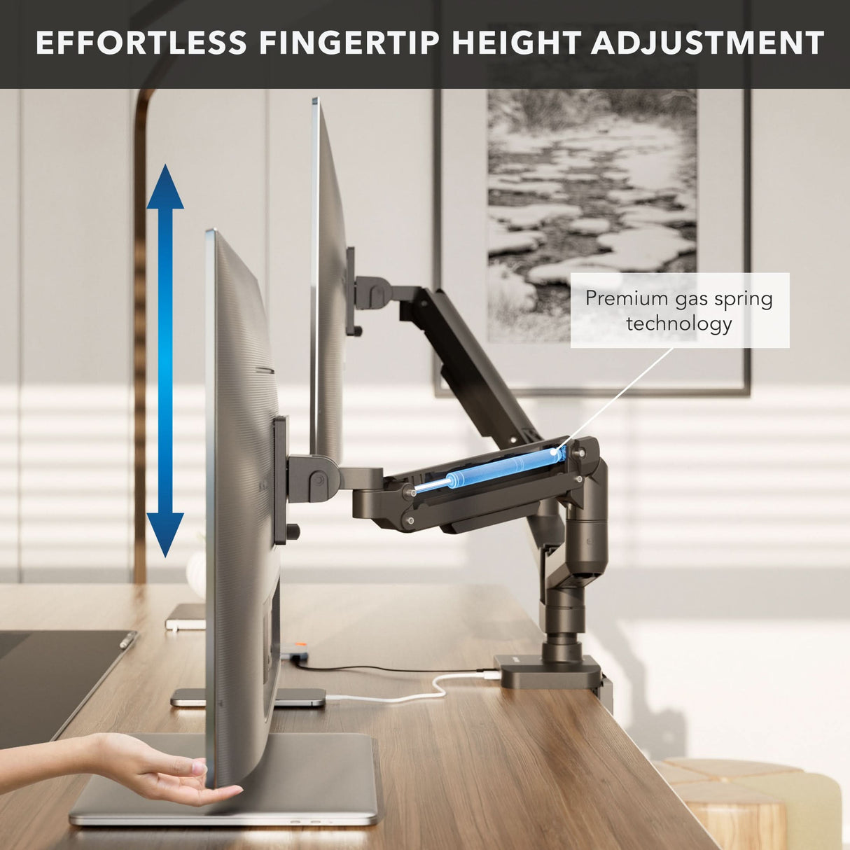 A user adjusts the height of the Mount-It! Heavy-Duty Dual Monitor Mount with Gas Spring Arms using a black mount on an ergonomic desk. Blue arrows show vertical movement, and a label highlights its premium gas spring technology.