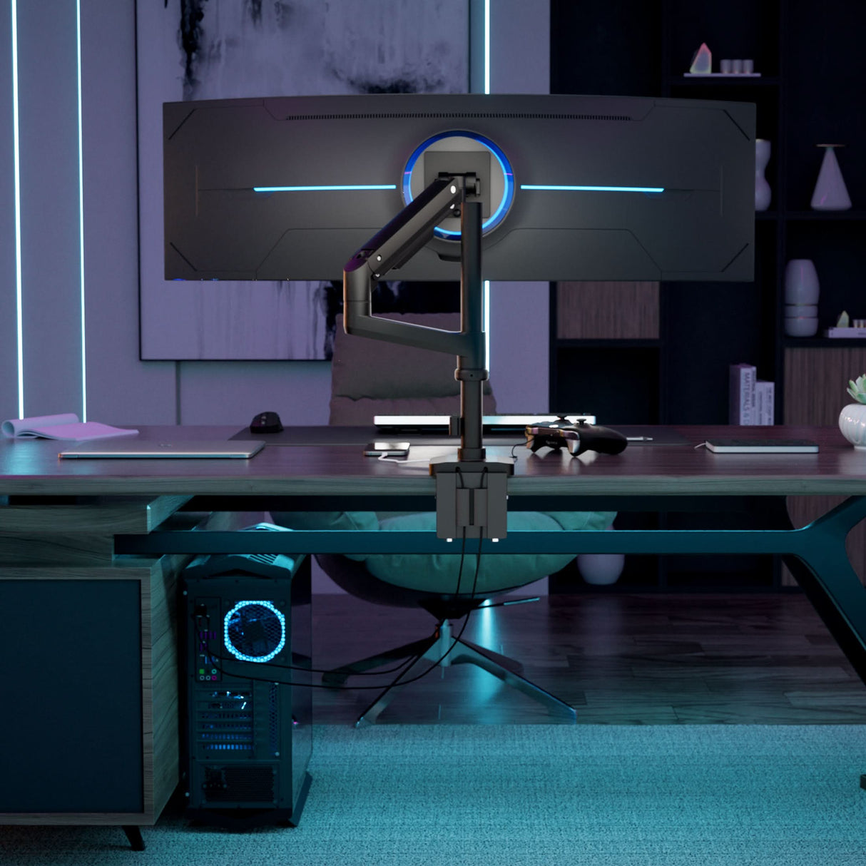 A modern workspace with a large curved monitor on the Mount-It! Heavy-Duty Monitor Mount with Pole & Gas Spring Arm, blue ambient lights, a gaming controller, and an illuminated desktop PC under a sleek desk.