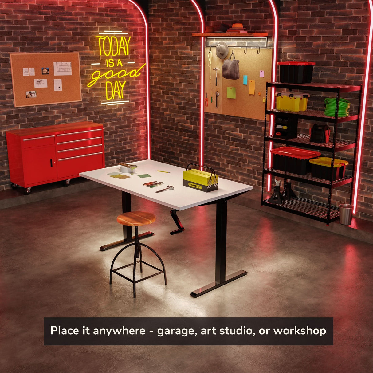 A modern workspace featuring the Mount-It! Hand Crank Standing Desk Frame with 48" tabletop, a wooden stool, red tool chest, shelving with bins, corkboards, and a “Today is a good day” neon sign—perfect for garage, studio, or workshop.