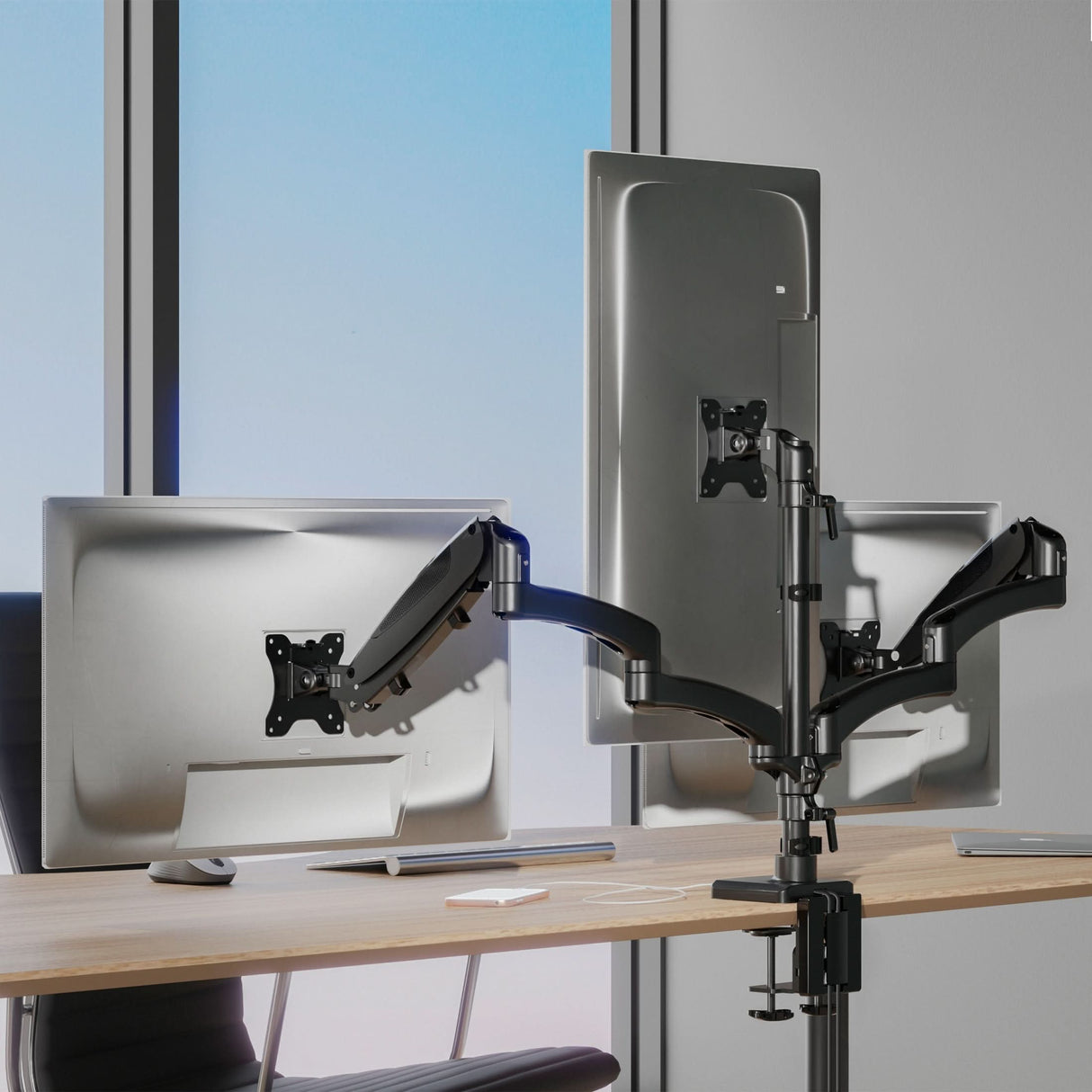Triple Monitor Mount with Gas Spring Arms and USB Ports installed on a desk near a window, featuring three adjustable monitors held by sturdy gas spring arms allowing tilt, swivel, and rotation for ergonomic comfort, with the mount clamped securely to the edge of the desk, designed to support multiple screens while saving space and offering integrated USB connectivity for device charging and accessory connection.