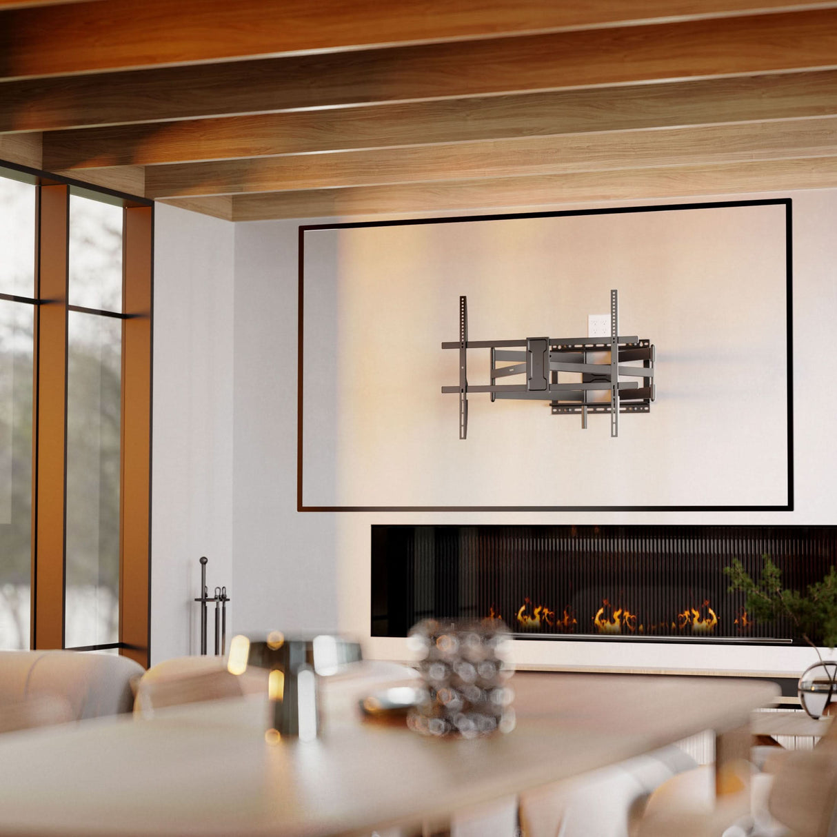 A modern living room with the Mount-It! Full Motion TV Wall Mount with Extra Long Extension above a linear fireplace, exposed wooden ceiling beams, neutral furnishings, large windows, and a contemporary, cozy vibe.