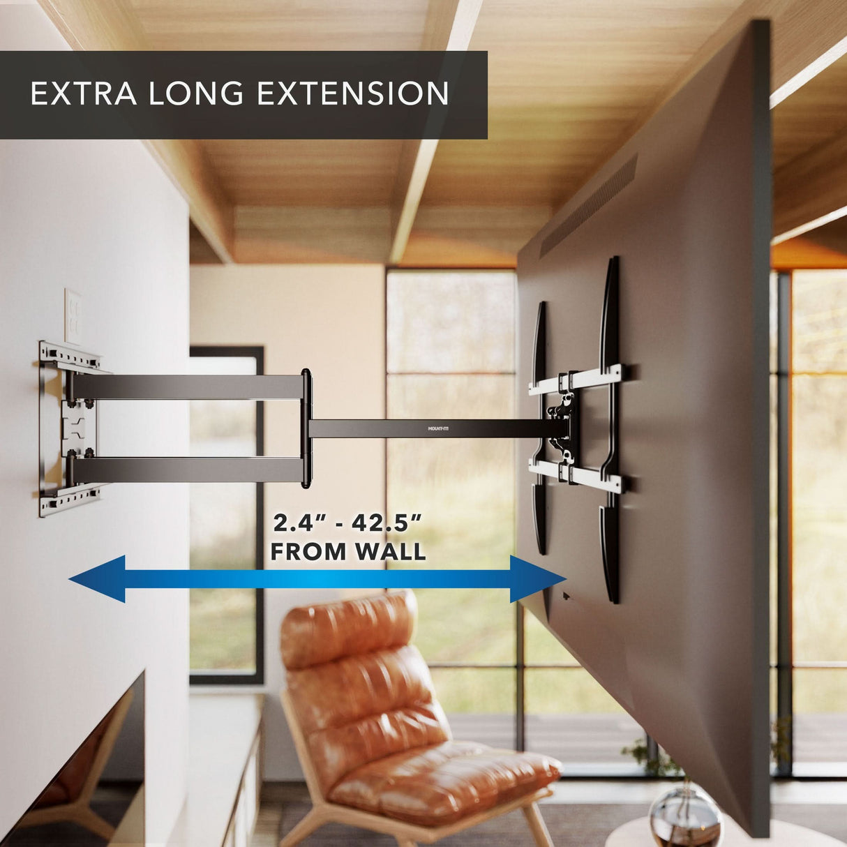 A wall-mounted TV is displayed on the Mount-It! Full Motion TV Wall Mount with Extra Long Extension, with its arm extending 2.4 to 42.5 inches from the wall. A modern living room and a chair appear in the background.