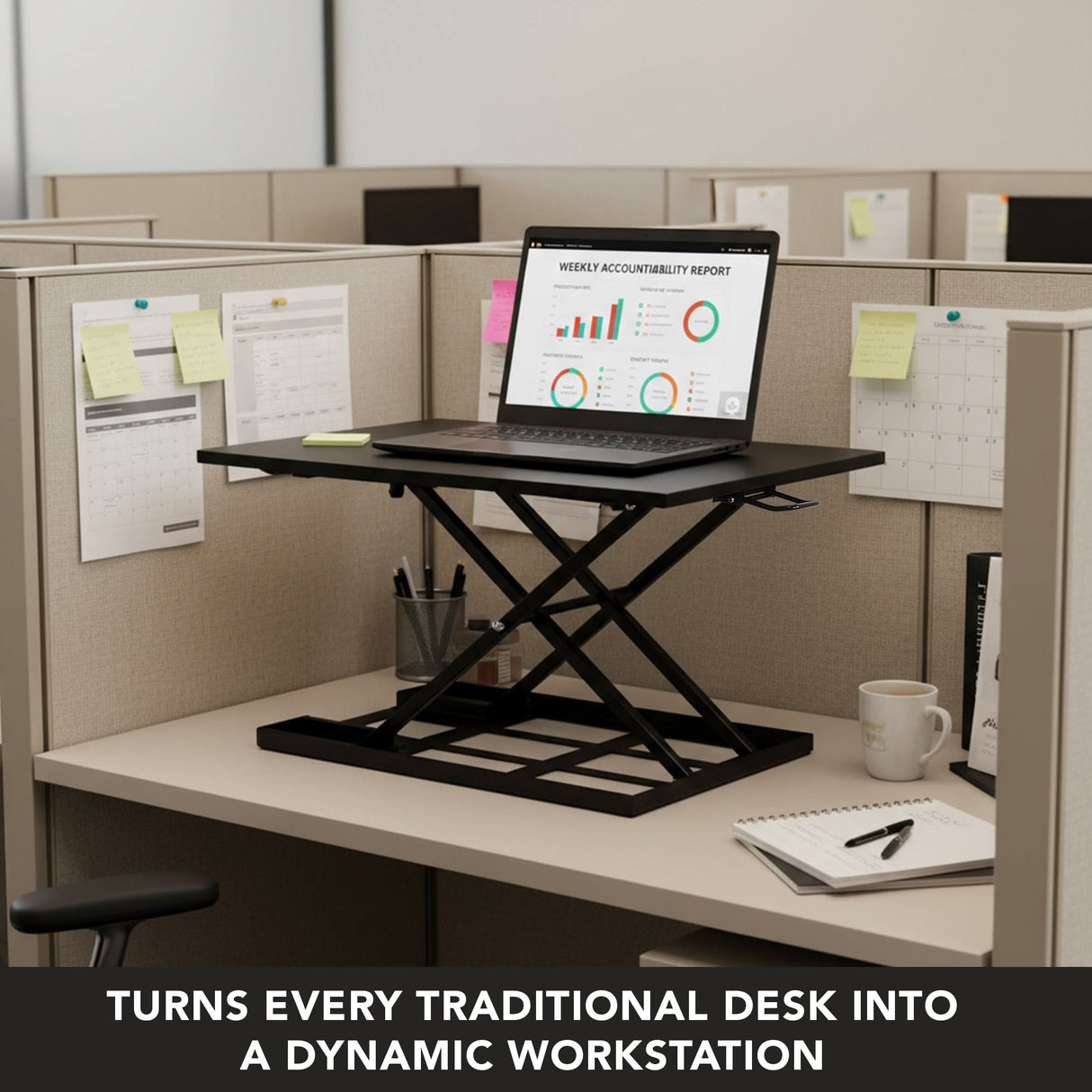 A Mount-It! Height Adjustable X-Lift Standing Desk Converter with a laptop is on a cubicle desk amid office supplies, charts, and calendars. Text below reads: Turns any traditional desk into an ergonomic, dynamic workstation.