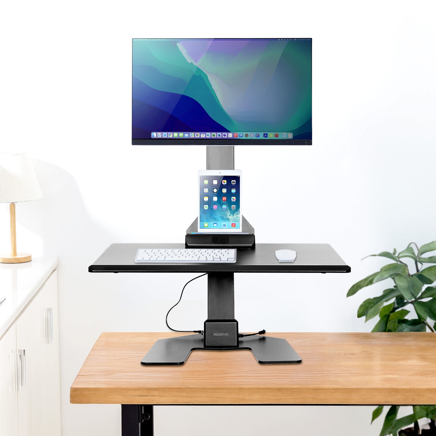 Adjustable standing desk converter with computer monitor and tablet on a wood desk and white background