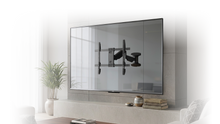 A flat-screen TV is mounted on a wall with a black metal TV bracket visible in the center, above a soundbar and round coffee table in a modern living room.