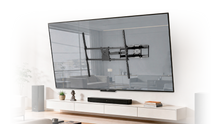 A wall-mounted flat-screen TV with a black TV mounting bracket visible, above a soundbar and a round coffee table in a modern living room.
