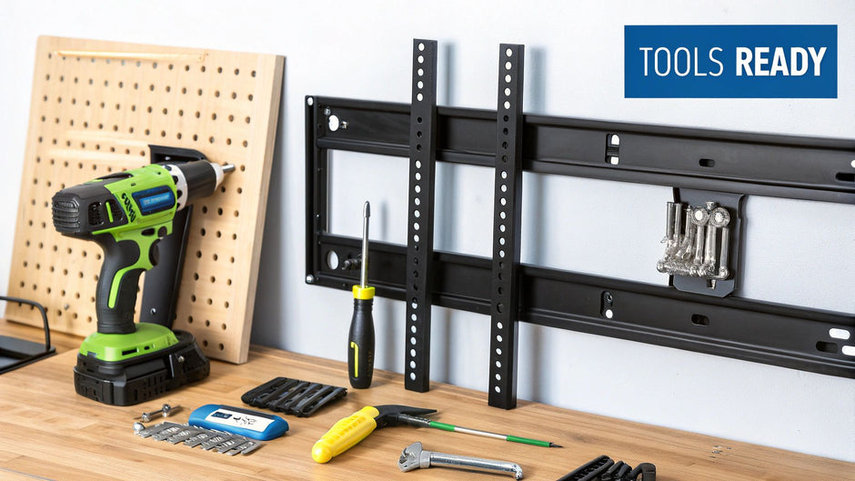 A workbench with various tools organized on its surface including a green and black cordless drill, a screwdriver, a set of drill bits, a wrench, and other small hand tools, positioned next to a pegboard and a black metal wall mount bracket attached to a light gray wall, with a blue sign reading "TOOLS READY" in the background.