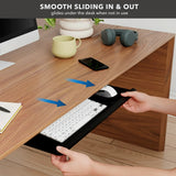 A person slides the Mount-It! Adjustable Keyboard Tray and Mouse Platform w/ Wrist Rest Pad under a wooden desk with accessories on top. Blue arrows show smooth sliding motion. Text above reads: “Smooth sliding in & out.”.