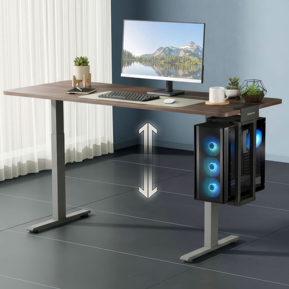 A modern office with a height-adjustable desk features a monitor, keyboard, mouse, plant, and a large PC tower secured in the Mount-It! Heavy-Duty Clamp-On CPU Mount with blue fans. An arrow highlights the desk's adjustable height.