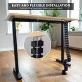 Cable Management Spine installed under a sit-stand desk showing flexible snap-together segments that route cables neatly from the floor to the desktop, demonstrating easy and customizable placement for organized workspace cable management with protection and strain relief.
