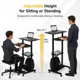 Two men use the Mount-It! Height Adjustable Rolling Stand up Desk—one sitting and typing at a lower level, the other standing at the raised cart. Its height adjusts from 37.4" to 54.7" and locking casters make moving it easy.