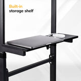 A close-up of the black built-in storage shelf on the Mount-It! Mobile Lectern Stand Up Desk, holding a closed laptop and wireless mouse, with “Built-in storage shelf” text in the upper left corner.