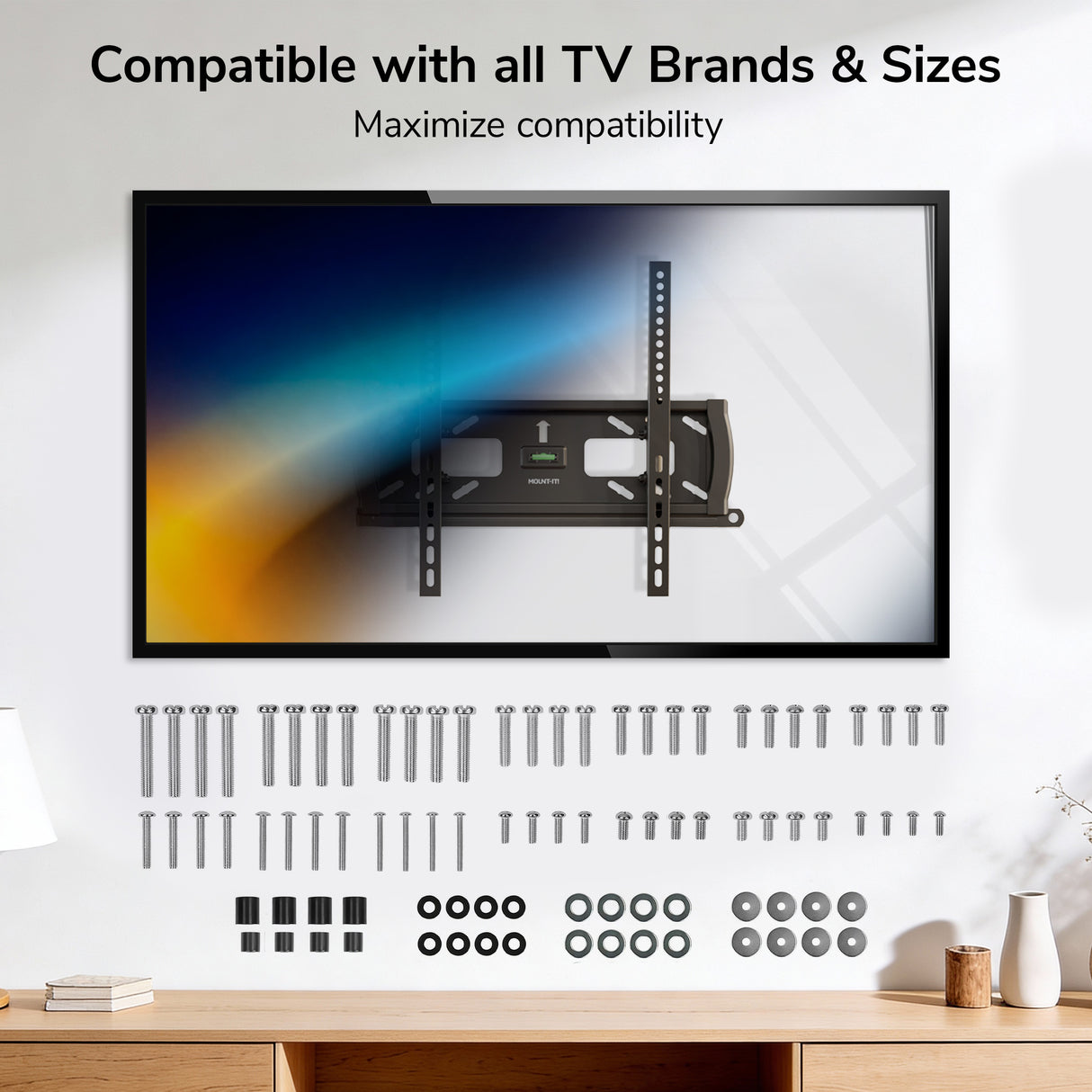 A wall-mounted flat-screen TV is shown above the Mount-It! TV Hardware Kit, which includes screws, bolts, washers, and spacers—demonstrating compatibility with all TV brands and sizes. Text: Compatible with all TV Brands & Sizes.